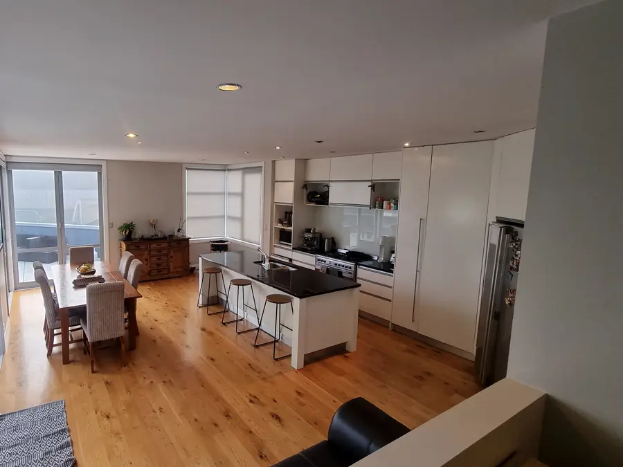The kitchen before the renovation, with white cabinets and a black benchtop